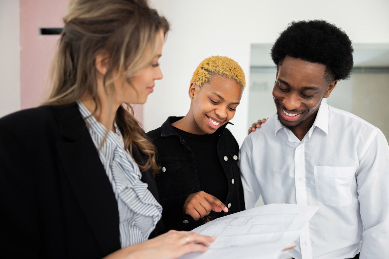 Real estate agent explains the home renovation plan as couple looks on with keen interest impressed by the eco-friendly design happy family concept.