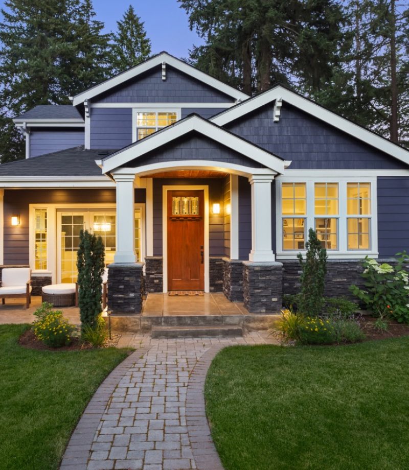 Beautiful home exterior in evening with glowing interior lights and landscaping.